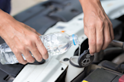 Person filling up their wiper fluid with water