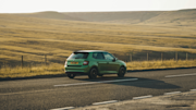 Green car travelling down a road