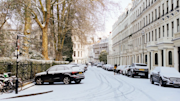 Snowy street in London with parked cars on either side
