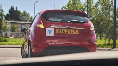 A red Ford fiesta indicating left out of a junction