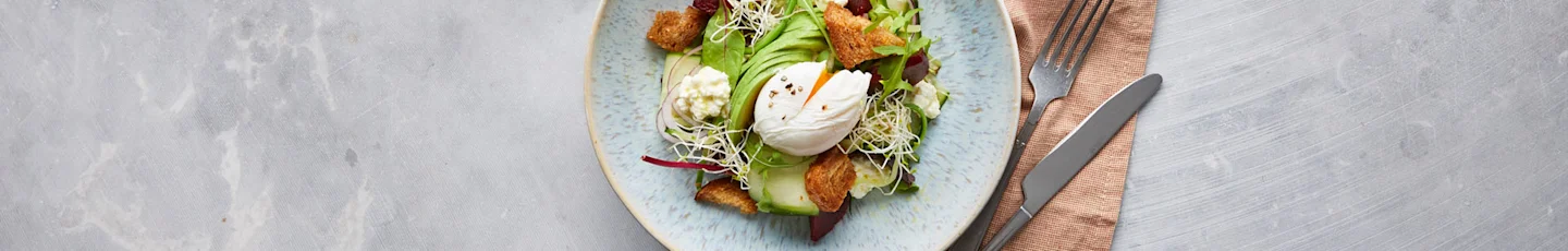 Vegetarisch recept van salade met avocado, gepocheerd ei, croutons en kiemgroenten.
