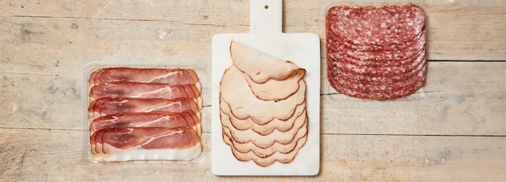 Drie soorten vleeswaren van PLUS Puur van Smaak: prosciutto, kalkoenfilet, en salami.
