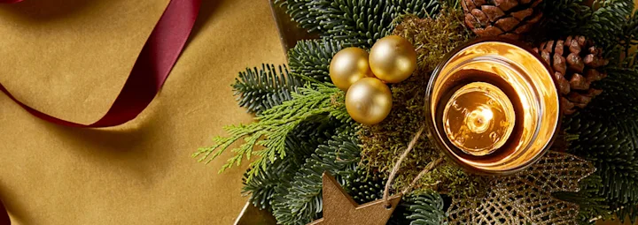 Sfeervolle kerstdecoratie met kaars, dennenappels en gouden accenten.