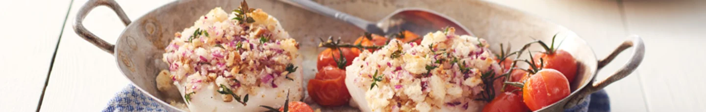 Skrei-vis en recept, omringd door verse ingrediënten zoals citroen, kruiden en groenten.