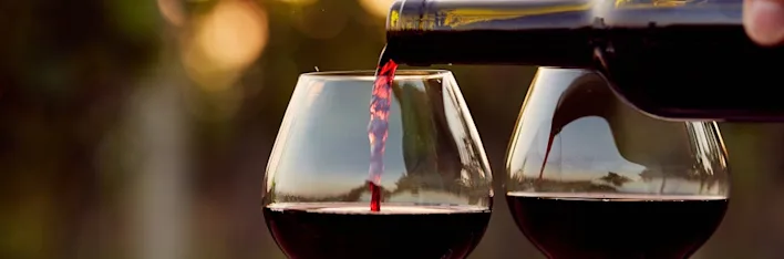 Rode wijn van PLUS wordt ingeschonken in een glas, met een tweede glas ernaast.