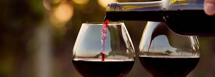 Rode wijn van PLUS wordt ingeschonken in een glas, met een tweede glas ernaast.