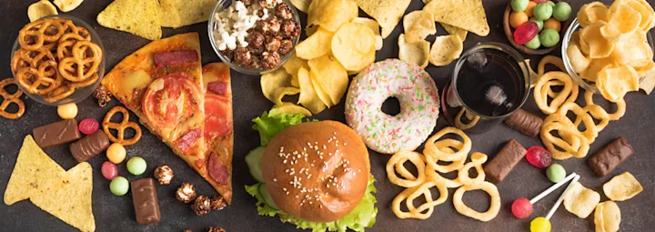 Snackselectie met onder andere pizza, hamburger, donut, chips, popcorn, snoep en frisdrank.