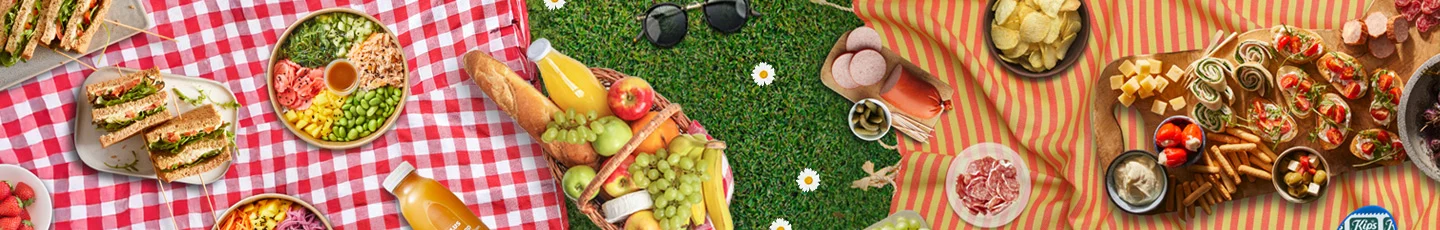 Picknick met sandwiches, salades, fruit, drankjes, chips, kaasblokjes, wraps en snacks.