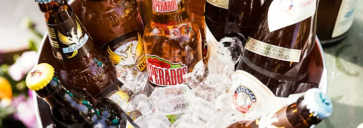 Selectie van bierflessen in een met ijs gevulde emmer. De flesjes zijn kleurrijk gelabeld met merken als Desperados en Erdinger.