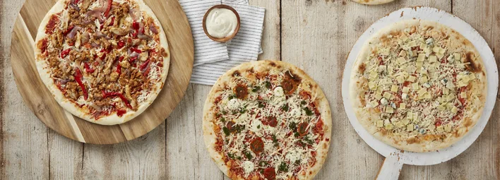 'Uit de keuken van PLUS' pizza's van pizza met champignons, paprika en rucola, salami, rode ui en kaas en een pizza met artisjok, olijven en verse basilicum.