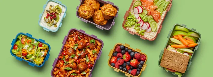 Verschillende LocknLock vershoudbakjes gevuld met diverse etenswaren, waaronder yoghurt, muffins, salades, pasta, gemengde bessen, en een sandwich.