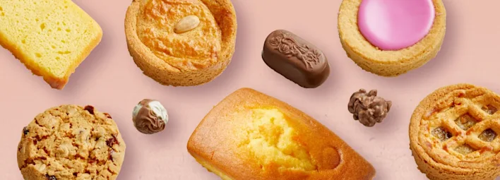 Assortiment van Korenlanders koekjes en chocolade op roze achtergrond.