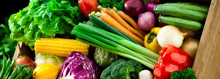 Kist vol verse groenten zoals paprika, wortel, broccoli, mais en sla.