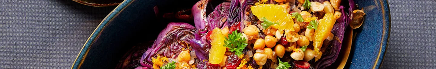 Winters gerecht van kleurrijke salade met geroosterde paarse kool, kikkererwten, sinaasappelpartjes, gedroogde cranberries en verse peterselie.