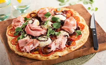 Hartige plaattaart met creme fraiche, abdijham, geitenkaas en trostomaten, rode ui en oregano