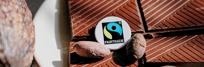 Chocolade met enkele cacaobonen en het Fairtrade-logo.