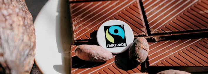 Chocolade met enkele cacaobonen en het Fairtrade-logo.