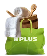 Groene PLUS-tas gevuld met wellnessproducten zoals een houten emmer, badborstel, witte handdoek en houten spatel.