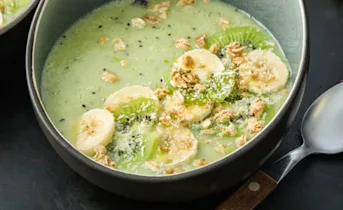 Groene smoothiebowl met kiwi, banaan, kokos en muesli