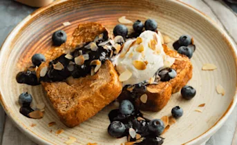 Wentelteefjes van suikerbrood met blauwe bessensaus