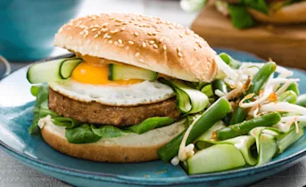 Broodje vegetarische hamburger met sperziebonensalade en satésaus