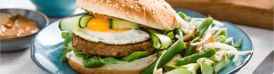 Broodje vegetarische hamburger met sperziebonensalade en satésaus