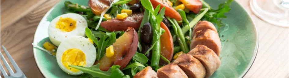 Zomerse maaltijdsalade met gebakken bonen en gegrilde worst
