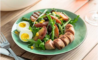 Zomerse maaltijdsalade met gebakken bonen en gegrilde worst