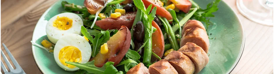 Zomerse maaltijdsalade met gebakken bonen en gegrilde worst