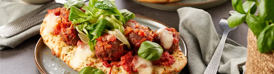 Rijkelijk belegde focaccia met gehaktballetjes in tomatensaus en mozzarella