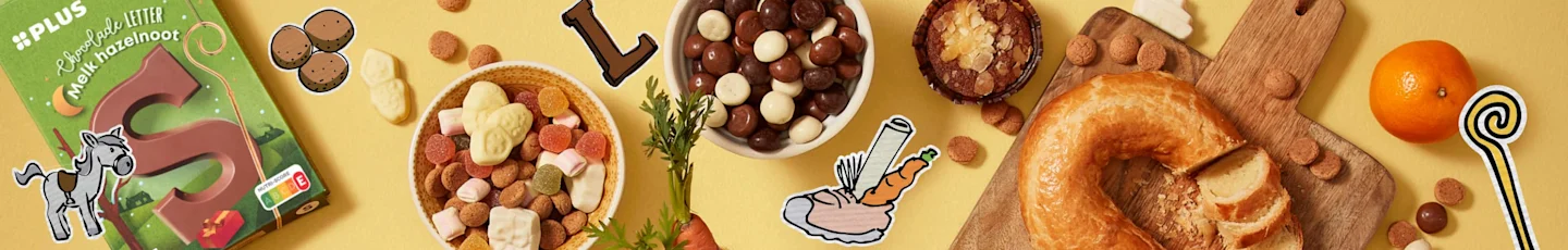 Sinterklaas-lekkernijen zoals o.a. een doos met een grote chocoladeletter “S”, twee schaaltjes gevuld met kleurrijke snoepjes en chocoladepinda’s.