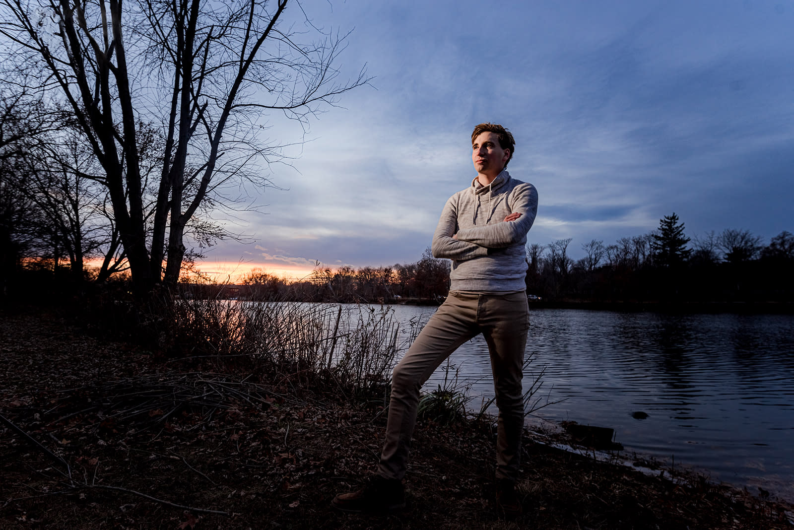 Author Jonathan standing in front of a lake while the sun sets behind him