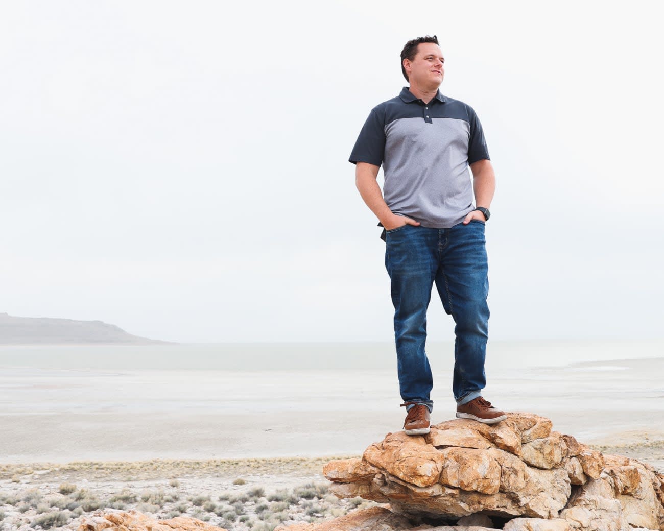 Photo of Tanner Linsley on the beach standing on a rock.