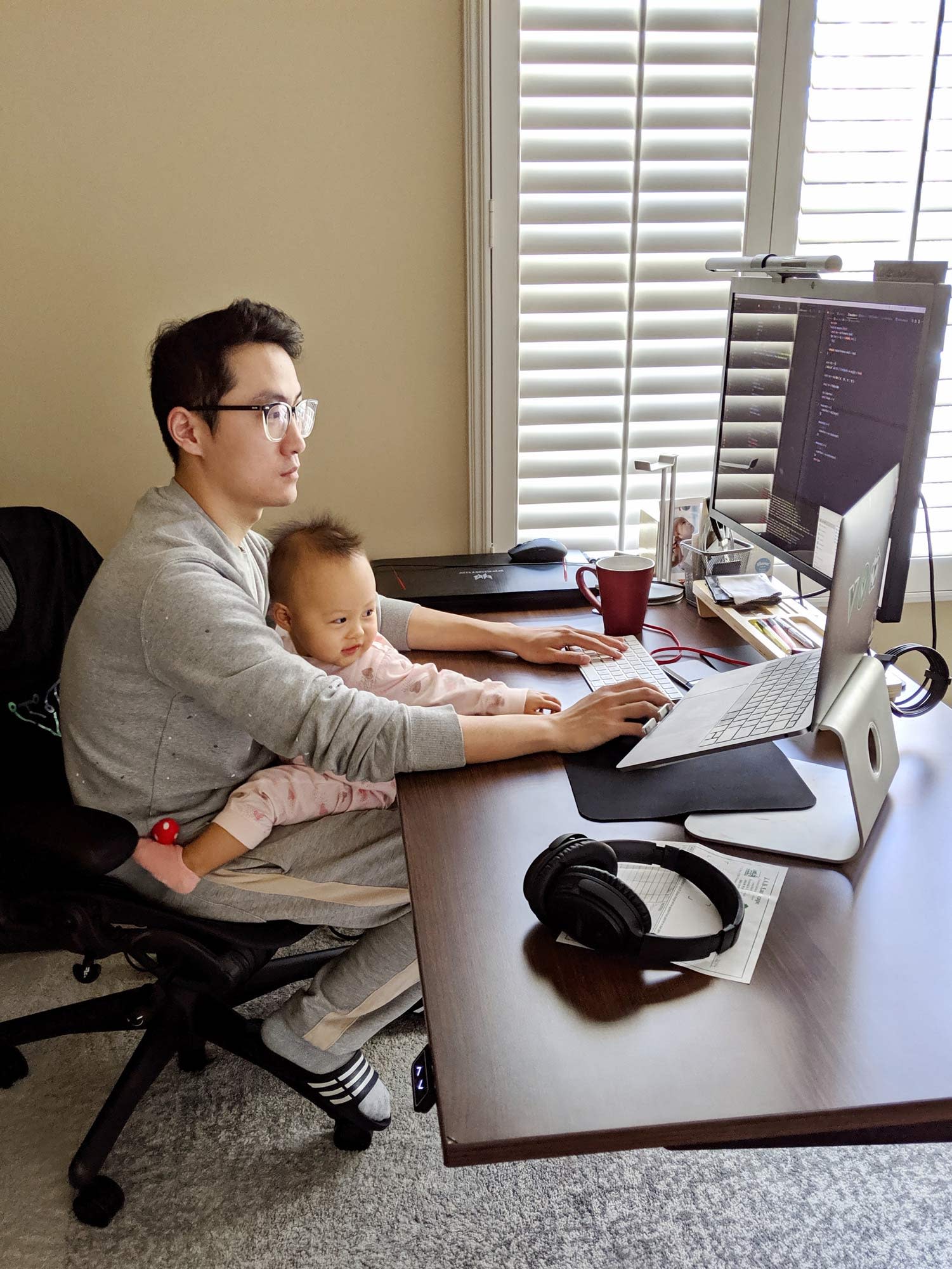 Photo of Evan You working at his desk with his child in his lap.
