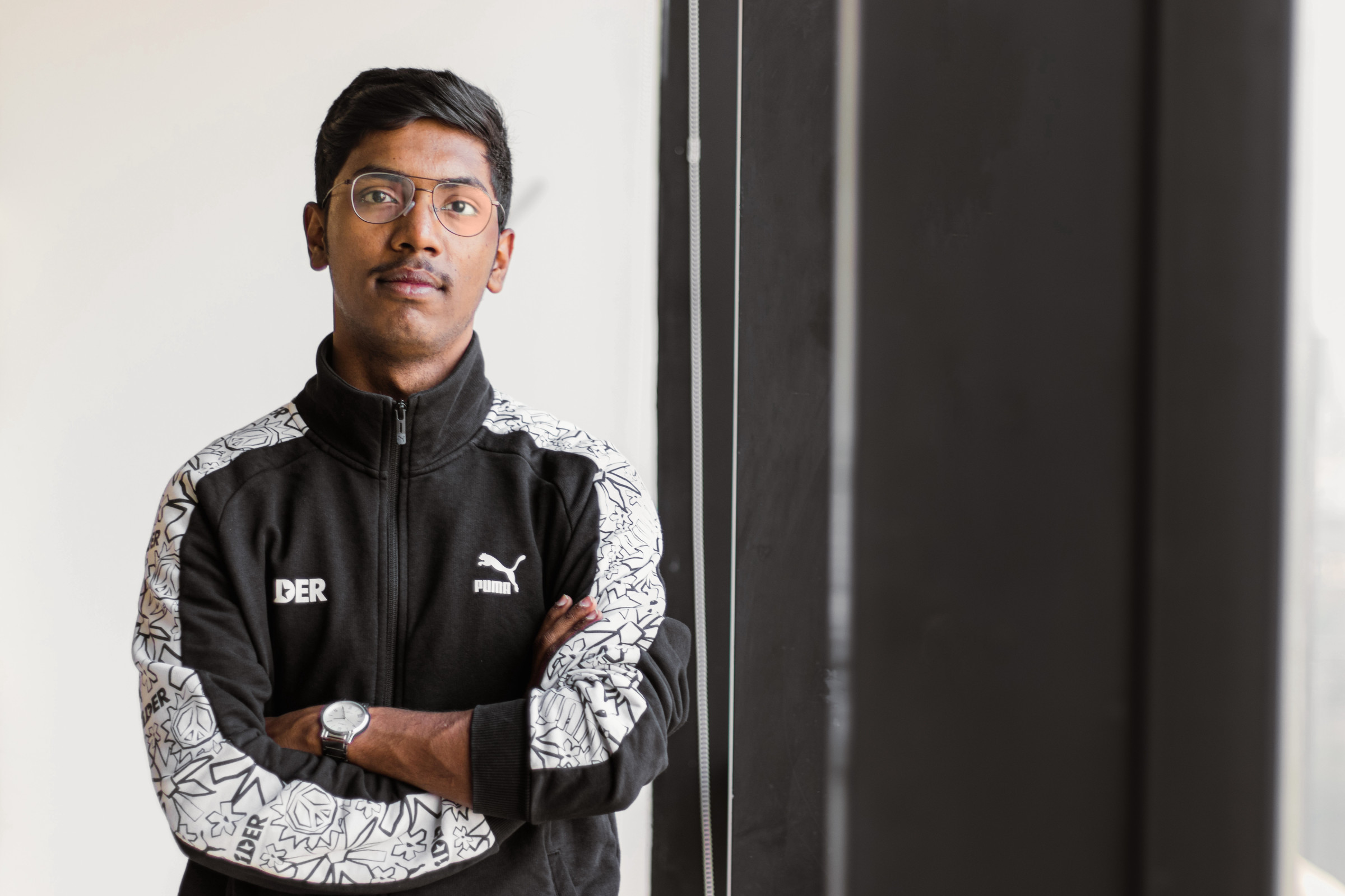 Author Rohan in a black-and-white Puma jacket against a white-and-black background, looking straight on at the camera