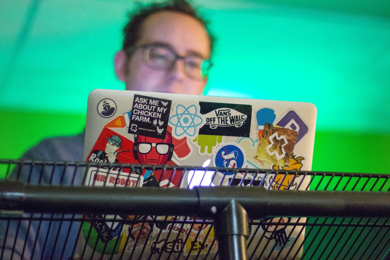Photo of a developer using a MacBook covered in stickers including a React sticker.
