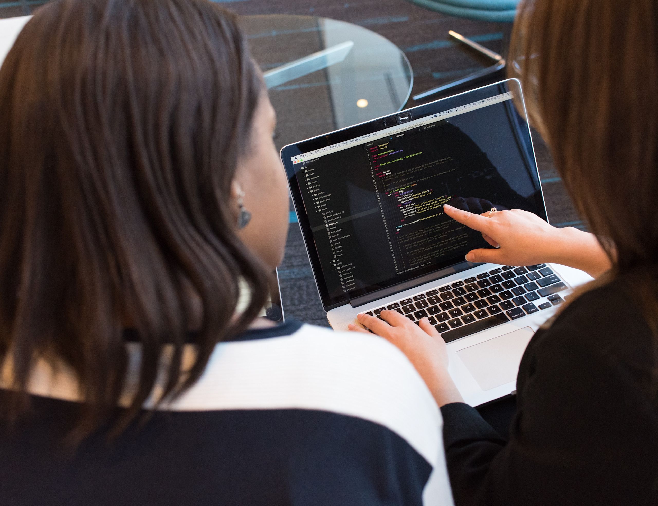 Two women discussing a piece of code