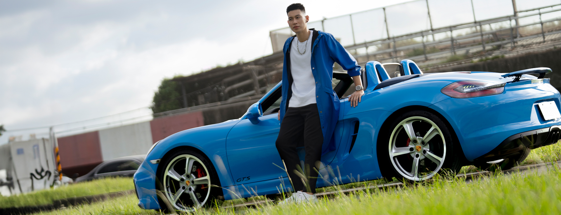 Jeremy Lin leans against Riviera Blue Porsche 718 Boxster GTS