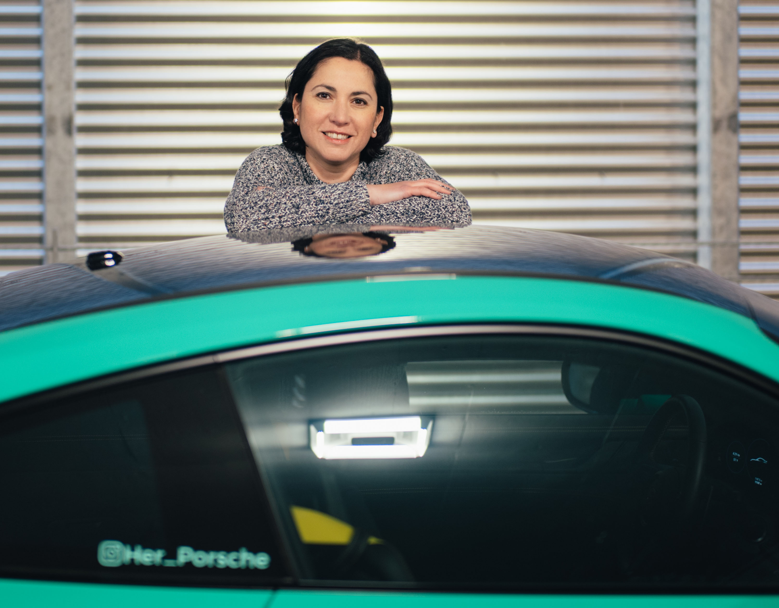 Smiling woman leaning over Jade Green Porsche 911 GT3