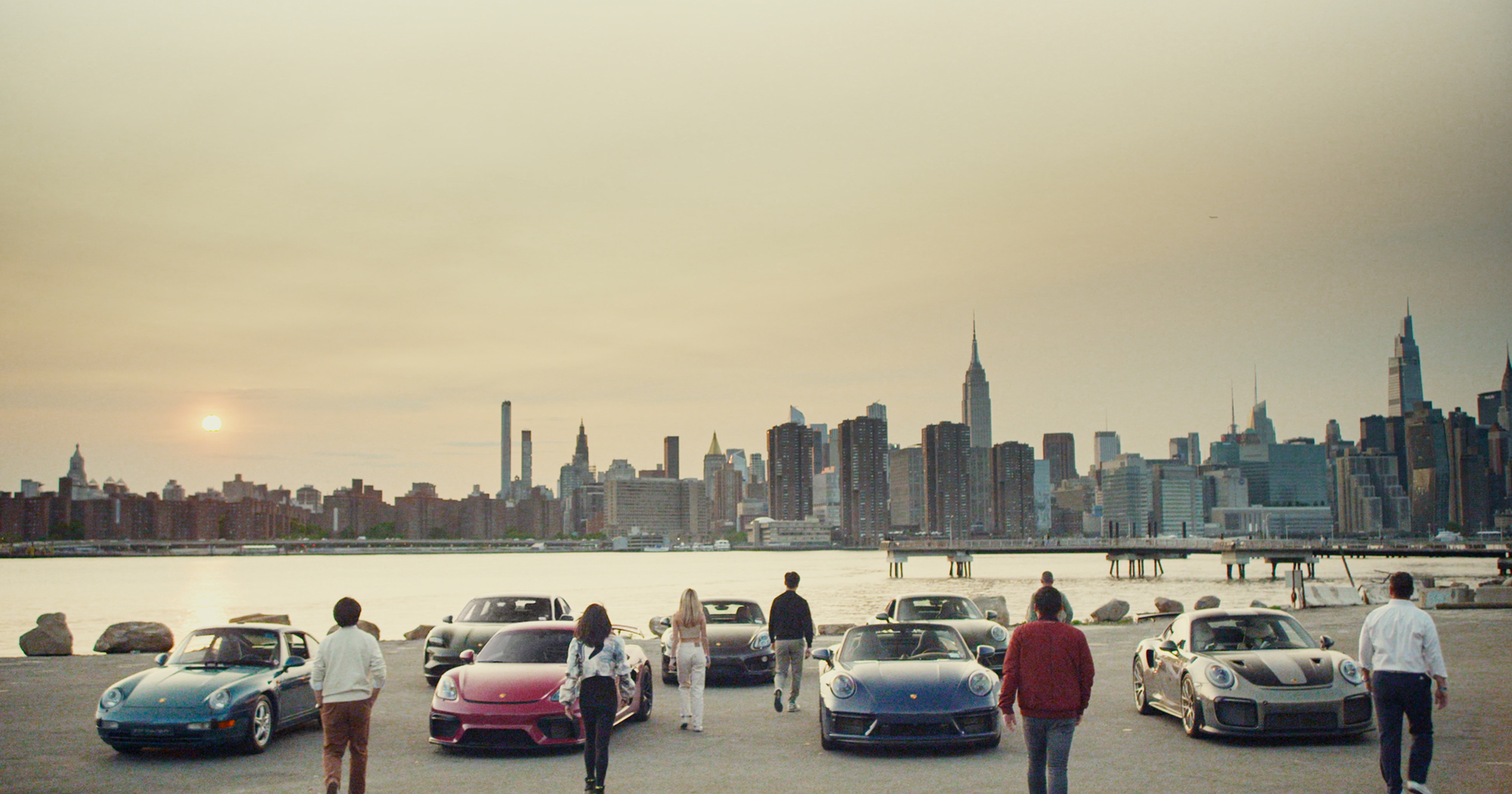 Men and women walks towards Porsche cars, Manhattan in background
