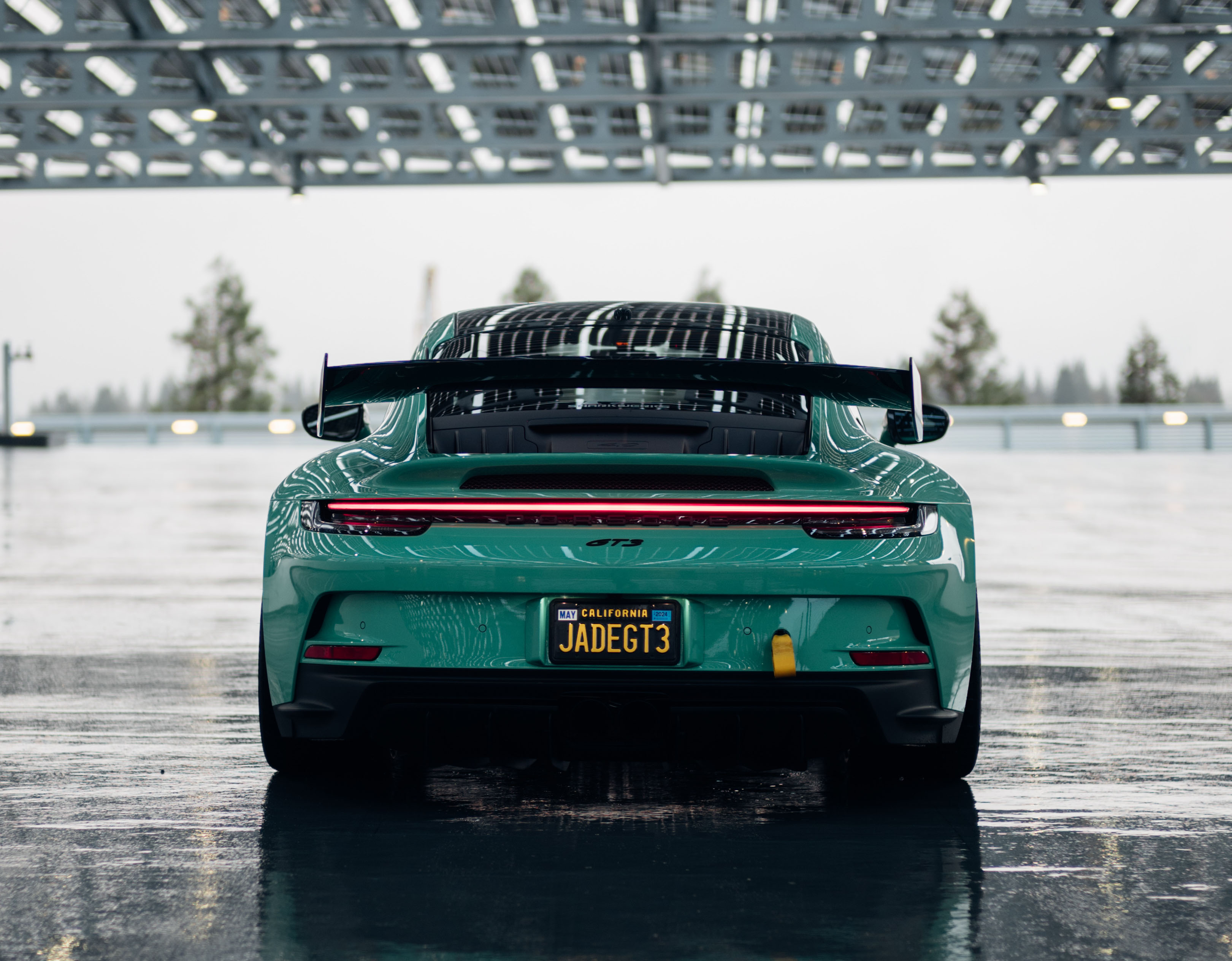 Green Porsche 911 GT3 in garage on rainy day