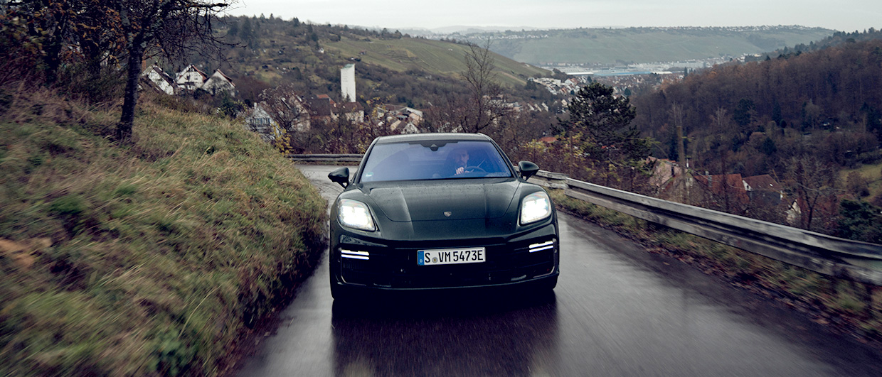 Dark green Porsche Panamera driving on wet, hilly road