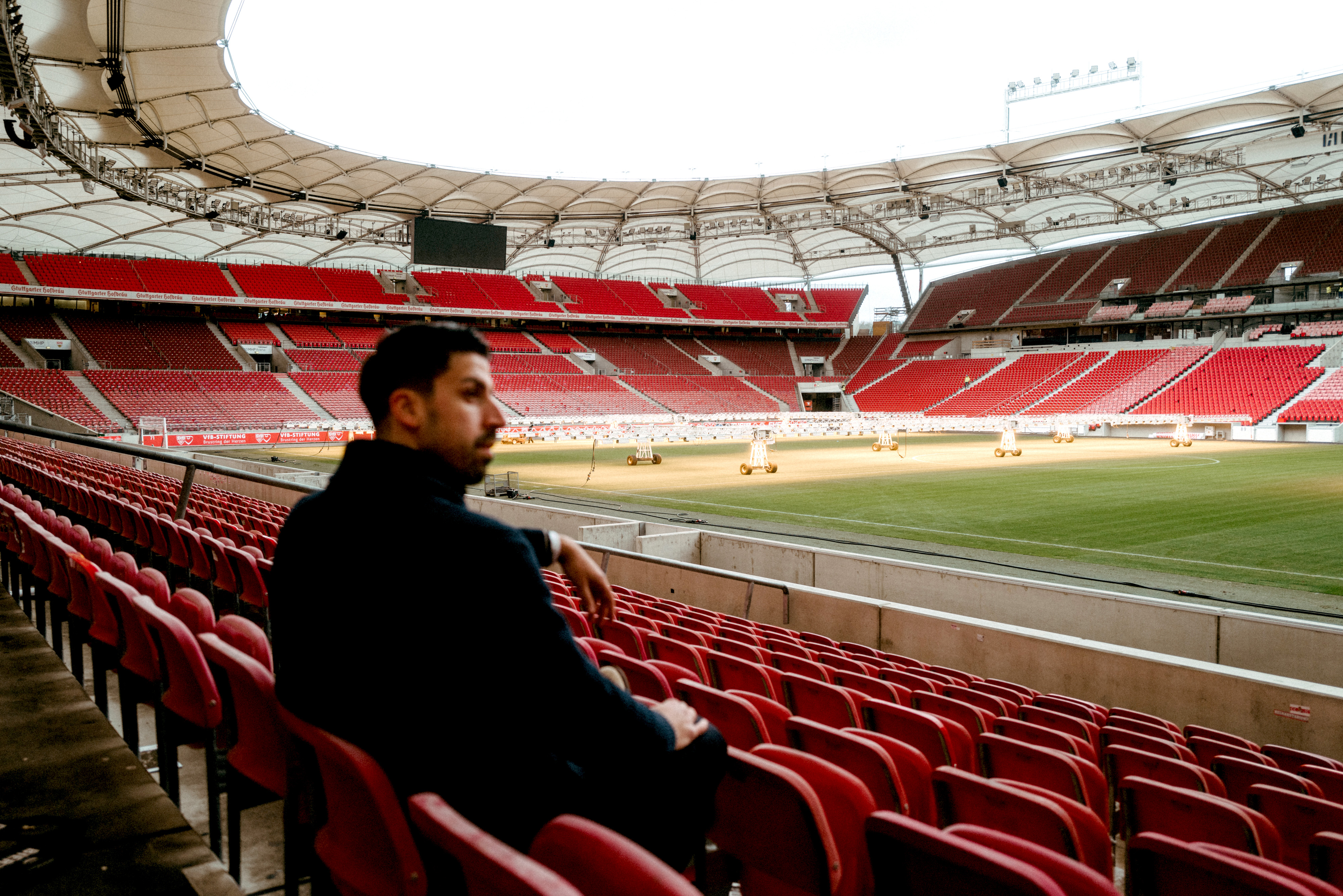 Man sitting in stands overlooking an empty football stadium