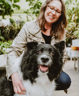 Woman holding Border Collie in garden centre