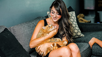 GO-SOLUTIONS-pet-parent-cuddling-with-ginger-cat-on-couch