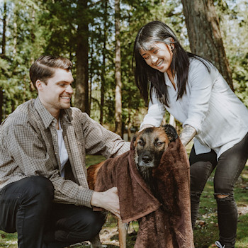 Man and woman drying off dog in towel