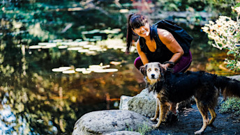 Black and brown dog and pet parent by pond