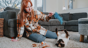 Girl with red hair playing with cat in living room