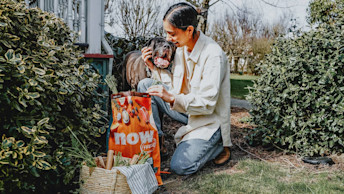 Pet parent and dog outdoors in garden with bag of Now Fresh