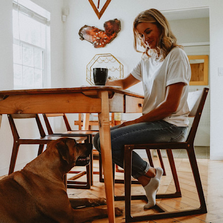 Woman reading at the table with dog laying on the floor